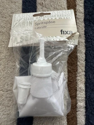 Spritsset med 5 tyllar från Fixa - Spritsset från Fixa med en vit spritspåse i tyg och fem olika plasttyllar. Perfekt för att dekorera bakverk och tårtor med olika mönster. Allt ligger i originalförpackning och är enkelt att använda för både nybörjare och proffs.