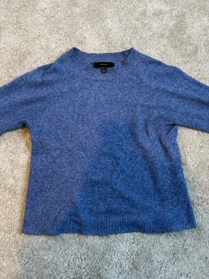 Blå stickad tröja  - Har ett hål vid nacken 