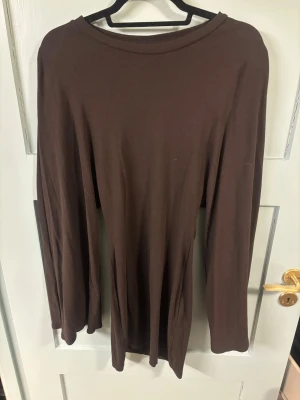 Brun långärmad topp i bomull - En enkel och stilren brun långärmad topp med rund halsringning. Tillverkad i mjuk bomull som känns skön mot huden. Perfekt att matcha med jeans eller kjol för en clean look.