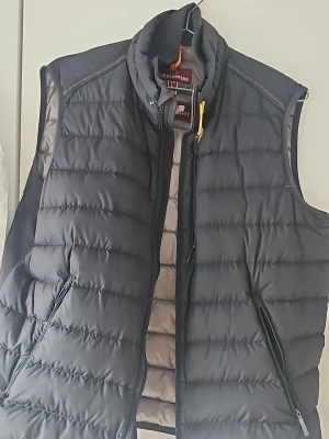 Parajumpers väst - Hej!  Säljer snygg och varm Parajumpers (PJS) vadderad väst i svart. Klassisk modell med hög krage, rejäl kvalitet och Parajumpers typiska detaljer.   Perfekt som mellanlager eller ytterplagg under vår/höst.   Västen är i bra skick, inga hål, inga trasiga sömmar eller dragkedjor.   Normal användning men väl omhändertagen.  • Hel dragkedja framtill • Två sidofickor med dragkedja • Hög krage • Original Parajumpers  Storlek: L  Priset kan diskuteras vid snabbaffär.  För mer info/intresse hör av er!