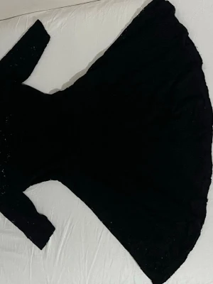 Svart spetsklänning från Chic a Booti - Svart klänning från Chic a Booti med vackra spetsdetaljer och medelärmad design. Klänningen har en elegant och feminin siluett med genombrutet mönster i tyget. Perfekt för dig som vill sticka ut med en klassisk look.