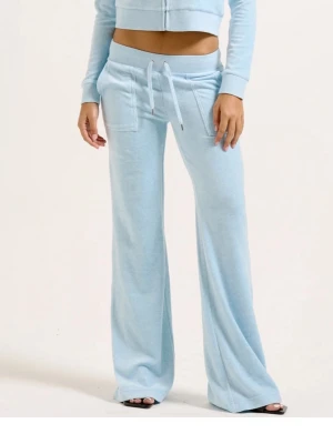 Ljusblå mjukisbyxor Juicy Couture - Ljusblå mjukisbyxor från Juicy Couture med utsvängda ben, bred resår i midjan och dragsko. Byxorna har stora fickor framtill och broderad logga på ena fickan. Tillverkade i mjuk velour som känns superbekväm.