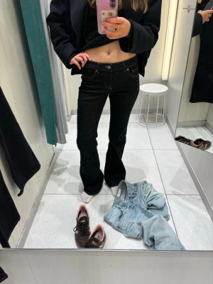 Svarta bootcut jeans med kontrastsömmar - Säljer ett par svarta bootcut jeans med snygga kontrastsömmar i gult. Jeansen har klassisk femficksmodell och hög midja. Materialet känns stretchigt och bekvämt, perfekt för dig som vill ha en cool och tidlös look. Använda 2 gånger, har inga mått. Jag är 165cm