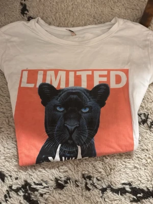Vit t-shirt med pantermotiv - Passar till en Xxs och en Xs också.Cool vit t-shirt med tryck av en svart panter och texten 'LIMITED' i vitt på en röd bakgrund. T-shirten har rund hals och korta ärmar, perfekt för en avslappnad och trendig stil. ❌T-shirten har två fläckar, ska försöka ta bort dom.❌
