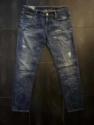 Slitna blå jeans från Polo Ralph Lauren - Snygga blå jeans från Polo Ralph Lauren med klassisk femficksdesign och slitna detaljer för en avslappnad look. Jeansen har en rak passform och är tillverkade i denim med en autentisk tvätt. Perfekta för dig som gillar en casual och trendig stil.