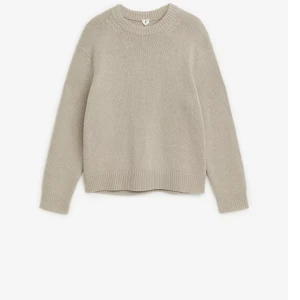 Beige stickad tröja med rund hals - En stilren beige stickad tröja med rund halsringning och långa ärmar. Tröjan har ribbade muddar vid ärmslut och nederkant, vilket ger en klassisk och avslappnad look. Perfekt att matcha med jeans eller kjol för en enkel och snygg outfit. Storlek XS för män men den är M i storleken för dam.