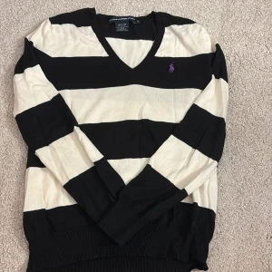Randig v-ringad tröja från Ralph Lauren - Snygg v-ringad tröja från Ralph Lauren Sport i svart och beige med breda ränder. Tröjan har lång ärm och är i nästan nyttskick! Säljer denna för jag inte använder den längre och tröjan behöver en ny ägare! ❤️ pris kan diskuteras, tröjan sitter lite som en xs/s fast det står M