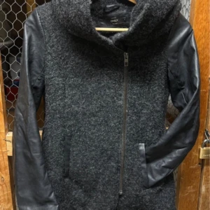 Grå jacka med skinnärmar från Only - Snygg grå jacka från Only med coola svarta skinnärmar och stor huva. Jackan har dragkedja framtill och två fickor. Perfekt för dig som gillar en urban och stilren look.