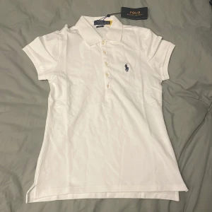 Vit pikétröja från Polo Ralph Lauren - Klassisk vit pikétröja från Polo Ralph Lauren i slim fit-modell. Tröjan har korta ärmar. Storlek M men liten i storleken så passar nog någon med storlek S. Pris kan diskuteras 