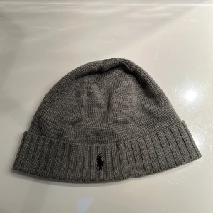 Grå mössa Polo Ralph Lauren - Snygg grå äkta mössa från Polo Ralph Lauren med klassisk svart broderad logga framtill. Hör av er vid frågor.
