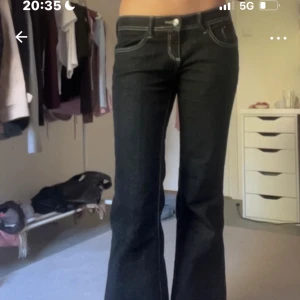 Mörkblå bootcut jeans med kontrastsömmar - Snygga mörkblå jeans från Gina tricot med bootcut passform och låg midja. Jeansen har tydliga vita kontrastsömmar, klassiska fem fickor och bälteshällor. Perfekta för dig som gillar en retro vibe och vill ha ett par jeans som sticker ut lite extra.