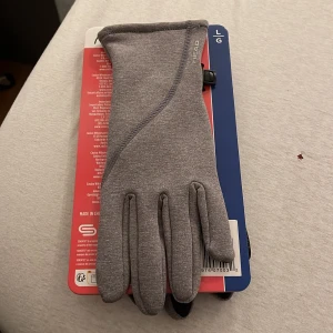 Grå löparhandskar från HEAD - Säljer ett par grå löparhandskar från HEAD med Sensatec-teknologi för touchskärm. Handflatan har svart silikonmönster för extra grepp och insidan är i stretchig fleece som känns mjuk och smidig. Perfekta för löpning när det är kallt ute.