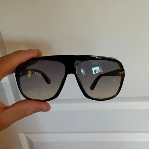 Svarta solglasögon Tom Ford - Tja! Säljer nu dessa snygga svarta solglasögon från Tom Ford med bred båge och stora, fyrkantiga linser i gradientton. Klassisk och modern look med tydlig logga på skalmen. Tillverkade i Italien och passar perfekt för både vardagsstil, men också mer uppklätt. 