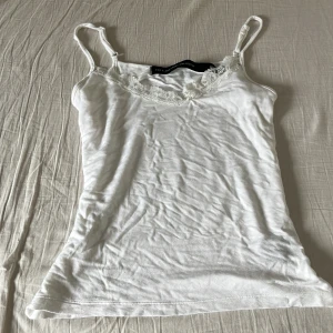 Vit linnetopp med spets  - Säljer en vit linnetopp från New Yorker i storlek M. Toppen har tunna axelband och vacker spetsdetalj längs urringningen. Perfekt att styla till jeans eller kjol. lite skrynklig men går absolut att stryka😇💕 kontakta för frågor