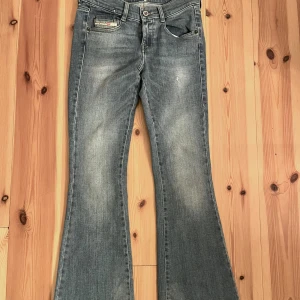 Diesel D-EBBEY bootcut jeans blå - Snygga blå bootcut jeans från Diesel, modell D-EBBEY. Jeansen har låg midja och klassisk femficksdesign med lätt slitningar och tvättade detaljer. Tillverkade i stretchig denim för skön passform. Perfekta för dig som gillar retrovibbar och markerade ben.
