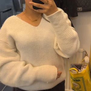 Vit stickad v-ringad tröja - Mysig vit stickad tröja med v-ringning och långa ärmar. Tröjan har en ribbad struktur och en lite loose passform som ger en avslappnad vibe. Perfekt att slänga på sig när det är kyligt ute. Passar mig som är i  storlek S/XS. Men själva tröjan är i storlek M 