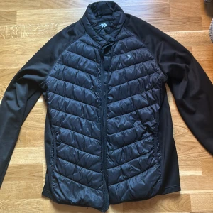 Svart Cardigan jacka - Svart carsigan ifrån 157 med quiltad framsida och rygg, hel dragkedja och långärmad design. Jackan är storlek L så passar om du är 184 plus