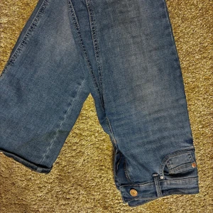 Vero moda jeans - Säljer ett par klassiska blå Levi's 513 jeans med raka ben och snyggt slitna detaljer vid benslutet. Jeansen har fem fickor, synliga sömmar och är tillverkade i robust denim. Perfekta för dig som gillar en avslappnad och tidlös look.