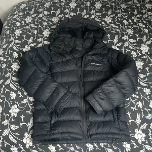  Peak Performance jacka  - Svart dunjacka från Peak Performance med huva och dragkedja. Jackan är quiltad och har en klassisk pufferstil med logga på bröstet. Ny pris:2500kr och är köpt på kids brandstore med storlek170-175