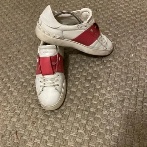 Valentino Garavani Open - Snygga Valentino Garavani Open sneakers i vitt skinn med bred röd läderdetalj.  De röda kan se lite rosa ut i vissa solljus. Priset inte satt i sten. Kan sänkas vid snabb affär
