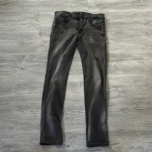 Replay svarta jeans med tvättad look - Snygga svarta jeans från Replay med tvättad och lite sliten look. Klassisk femficksmodell med Replay-logga på fickan och knappstängning. Jeansen har en rak passform och är tillverkade i mjukt jeanstyg som sitter skönt hela dagen.