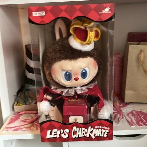 The MONSTERS Let's Checkmate Series Vinyl Plush Doll - Samlarfigur från POP MART, The MONSTERS Let's Checkmate-serien. Oöppnad originalförpackning, perfekt skick. Söt design med kungakrona och plyschdetaljer. Passar samlare och fans av designerleksaker. 