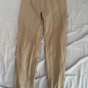 Beige seamless leggings från 157 - Snygga beige seamless leggings från 157 med ribbad midja och diskreta mönsterdetaljer längs benen. Stretchigt material som sitter tight och bekvämt, perfekt för träning eller chill. Stilren design utan synliga sömmar för en clean look🩷
