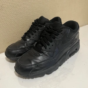 Nike Air Max 90 helsvarta sneakers - Säljer ett par helsvarta Nike Air Max 90 LTR sneakers med klassisk design och synlig Air Max-dämpning. Skorna har använts mindre än 2 dagar men de passade inte min fotform så de funkade inte för mig. De har inga skador eller någonting. Köpta för 1750kr.