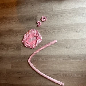 Rosa satin bonnet och hårband - Säljer en glansig rosa bonnet i satinmaterial, perfekt för att skydda håret under natten. Medföljer heatless curls och scrunchies. Bonneten har lite fläckar.💓