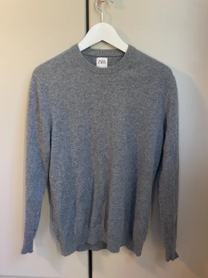 Grå kashmirtröja från Zara - Mjuk och stilren grå tröja från Zara i 100% kashmir. Rund halsringning och ribbade muddar vid ärmslut och nederkant. Perfekt för dig som gillar enkel och clean look med lyxig känsla. Passar dig som vill ha en klassisk tröja med skön passform. Nypris 1400kr