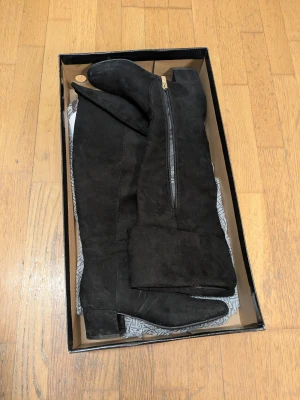 Svarta höga stövlar med dragkedja - Säljer ett par svarta höga stövlar med dragkedja på sidan och låg klack. Stövlarna har en klassisk design med rund tå och passar perfekt till både jeans och kjol. Snygga och stilrena för höst och vinter.