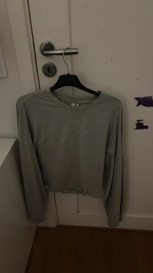 Grå långärmad tröja i bomull - En enkel och stilren grå långärmad tröja i mjuk bomull. Tröjan har rund hals och en loose passform som gör den skön att bära. Perfekt för chill dagar eller när du vill ha en clean look. Passar dig som gillar basic och minimalistisk stil.