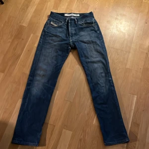 Blå jeans från Diesel Industry, strl 32 - Snygga blå jeans från Diesel Industry, tillverkade i Italien. Klassisk femficksmodell med raka ben och normal passform. Jeansen har coola slitningar och detaljer, samt en tydlig Diesel-patch bak i midjan. Perfekt för dig som gillar tidlös denimstil. Använda 1 gång.