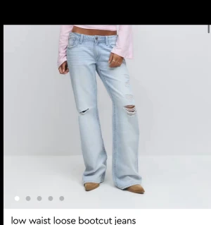 Loose bootcut jeans gina  - Snygga, eftertraktade och helt slutsåld ljusblå bootcut jeans med låg midja och loose passform. Jeansen har slitna detaljer och hål på låret och knät för en trendig look. Klassisk femficksmodell med knapp och dragkedja framtill. Perfekt för dig som gillar avslappnad stil. (ALDIG ANVÄNDA,PRISLAPP KVAR)