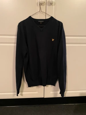 Mörkblå v-ringad Lyle & Scott tröja - Säljer denna mörkblåa v-ringade Lyle & Scott tröja i storlek XL. Den är i okej skick men är rätt använd. Tror inte att just denna modell fortfarande säljs men liknande modeller ligger runt 900kr. Hör av er vid eventuella funderingar!