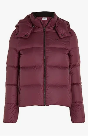 Vinröd pufferjacka Calvin Klein Jeans - Snygg vinröd pufferjacka från Calvin Klein Jeans med huva och dragkedja framtill. Jackan har två sidofickor med dragkedja och CK-logga på bröstet. Perfekt för kalla dagar och har en modern, boxig passform.
