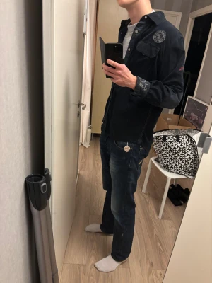 Mörkblå skjorta  från Camp David - Mörkblå skjorta från Camp David med broderade detaljer och tryck på ärm och rygg. Skjortan har knappar framtill, bröstficka och coola kontrastdetaljer på manschetterna, perfekt för lager-på-lager-stil. Pris inte 100% spikat