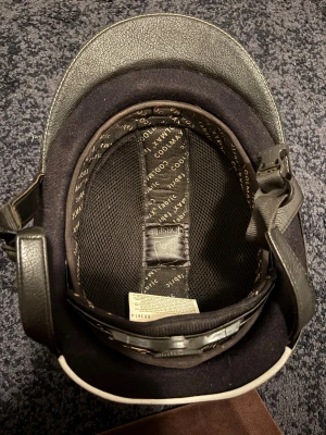 Brun/svart ridhjälm med silverdetaljer - Snygg ridhjälm i svart/svart med silverdetaljer och glittriga inslag. Hjälmen har en bred svart rem i mitten, ventiler med mesh och justerbart hakband. Insidan är fodrad med COOLMAX-tyg för extra komfort. Väl använd me några små repor åvanpå. Inga skador utifrån reporna. STR M/L. Skriv via e-mejl eller SMS då jag inte kan ta emot Swish vid detta nmr. Mobil 072-887 56 24 e-mejl emli.com@icloud.com MVH Emilia/marina😊