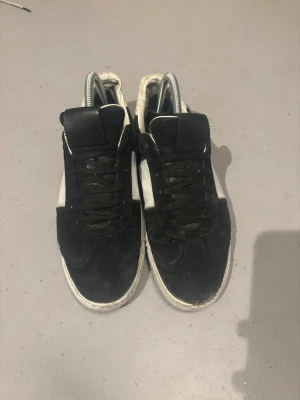 Valentino flycrew  - Snygga sneakers i svart och vitt med klassisk låg profil. Ovandelen är i mocka och skinn, med svarta snören och vit panel på sidan. Platt sula och rund tå ger en clean look som funkar till streetwear. Perfekt för dig som gillar stilrena och tidlösa sneakers.