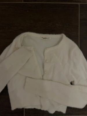 Vit fluffig kofta från Glamorous - Supermjuk och fluffig vit kofta från Glamorous Tall i storlek 36. Koftan har rund hals, långa ärmar och pärlknappar framtill. Passar även xs