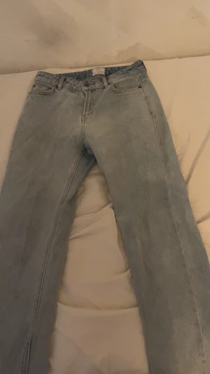 Ljusblå raka jeans från grunt - Säljer ett par ljusblå jeans från grunt med klassisk femficksdesign och raka ben. Jeansen har normal passform och är tillverkade i jeansmaterial med knapp och dragkedja framtill. Perfekt för dig som gillar enkel och clean stil.helt nya