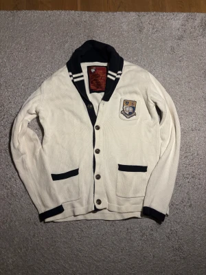 Unik Morris Cardigan  - Snygg vit, unik cardigan från Morris University Collection med mörkblå detaljer och broderat emblem på bröstet. Inga defekter eller liknande. Skriv vid frågor eller om du vill ha fler bilder☺️