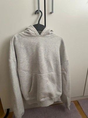 Ljusgrå hoodie från 157, storlek XS - Mjuk och skön ljusgrå hoodie från 157 i modellen Hilma. Tröjan har huva, stor magficka och ribbade muddar vid ärmslut och nederkant. Perfekt för chill dagar och har en loose passform. Materialet är fleece och polyester för extra komfort.