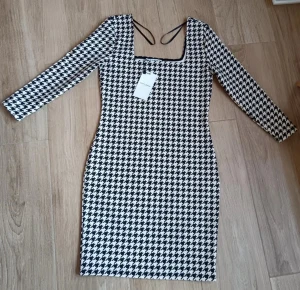 Bodycon Dress  - Supersnygg svartvit klänning från Easy Wear i storlek S. Den har ett klassiskt hundtandsmönster, lång ärm och fyrkantig ringning. Tight passform och kort längd, perfekt för dig som gillar en trendig och stilren look.