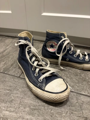 Mörkblå Converse All Star high tops - Säljer ett par klassiska mörkblå Converse All Star high tops med vit gummitå och sula. Väl använda men fortfarande jätte fina