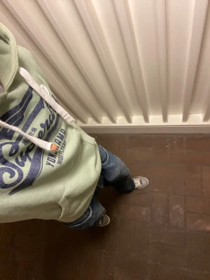 Superdry Hoodie - Snygg ljusgrön hoodie från Superdry med stort blått tryck på bröstet och vit JPN-text på ärmen. Klassisk känguruficka, vita snören i huvan och mjuk insida. Perfekt för dig som gillar streetstyle och japanska influenser. Om du undrar något är det bara att skriva🙌✅