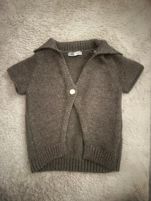 Stickad brun kofta från Zara - Säljer en stickad brun kofta från Zara med korta ärmar, krage och en vit knapp framtill! Pris kan diskuteras!❤️