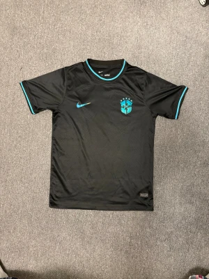 Brazil Fotbollströja  - Säljer en svart Brazil fotbollströja från Nike. Perfekt för dig som älskar fotboll och vill sticka ut på planen.