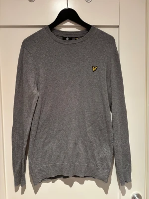 Grå stickad tröja från Lyle & Scott - Grå stickad tröja från Lyle & Scott med rund hals och lång ärm. Tröjan är i mycket bra skick och har storlek M.