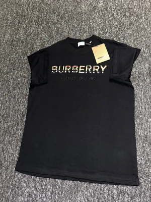 Svart Burberry t-shirt med logga - Svart t-shirt från Burberry med klassisk logga broderad på bröstet i beige, rött och svart. T-shirten har rund halsringning och korta ärmar. Tillverkad i mjuk bomull för en skön känsla och stilren look.